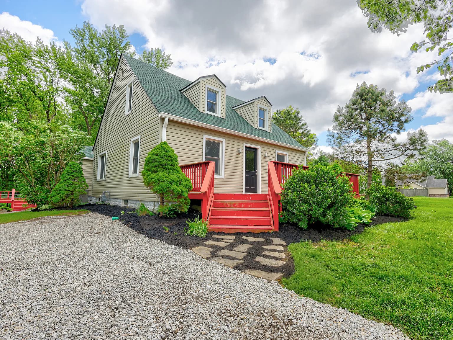 The red house — a green-roofed home with a bright red porch and steps